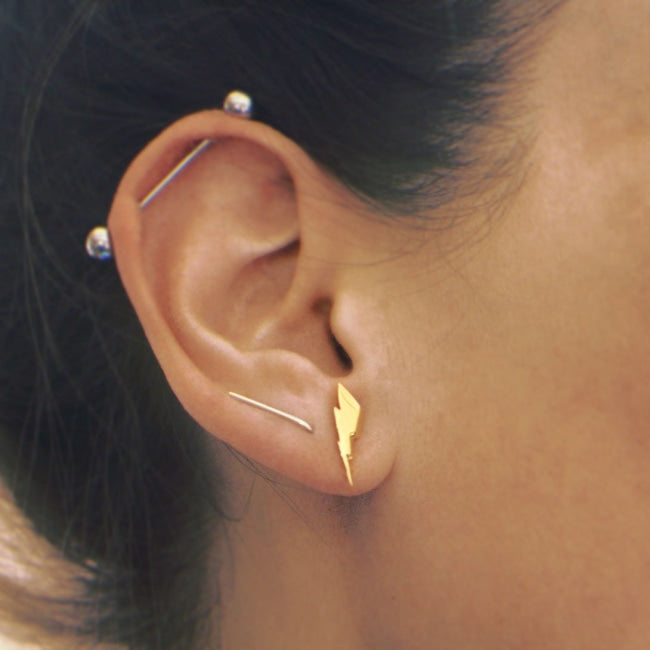 front view of the Mighty Morphin Power Rangers Bolt Earrings in gold on a woman with ear piercings