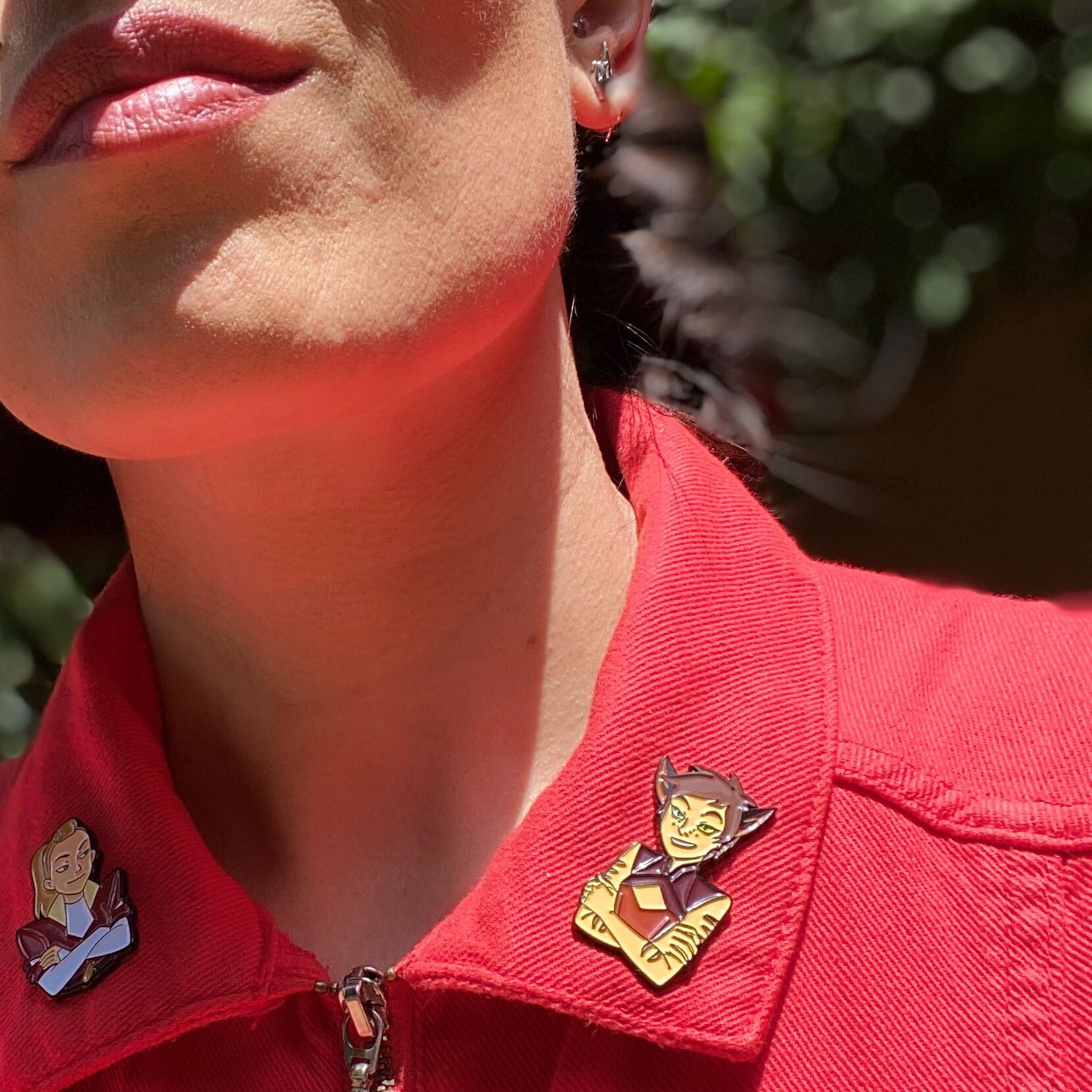 shot of a woman in a red collar top wearing the adorable catra and the adora pin on her collar