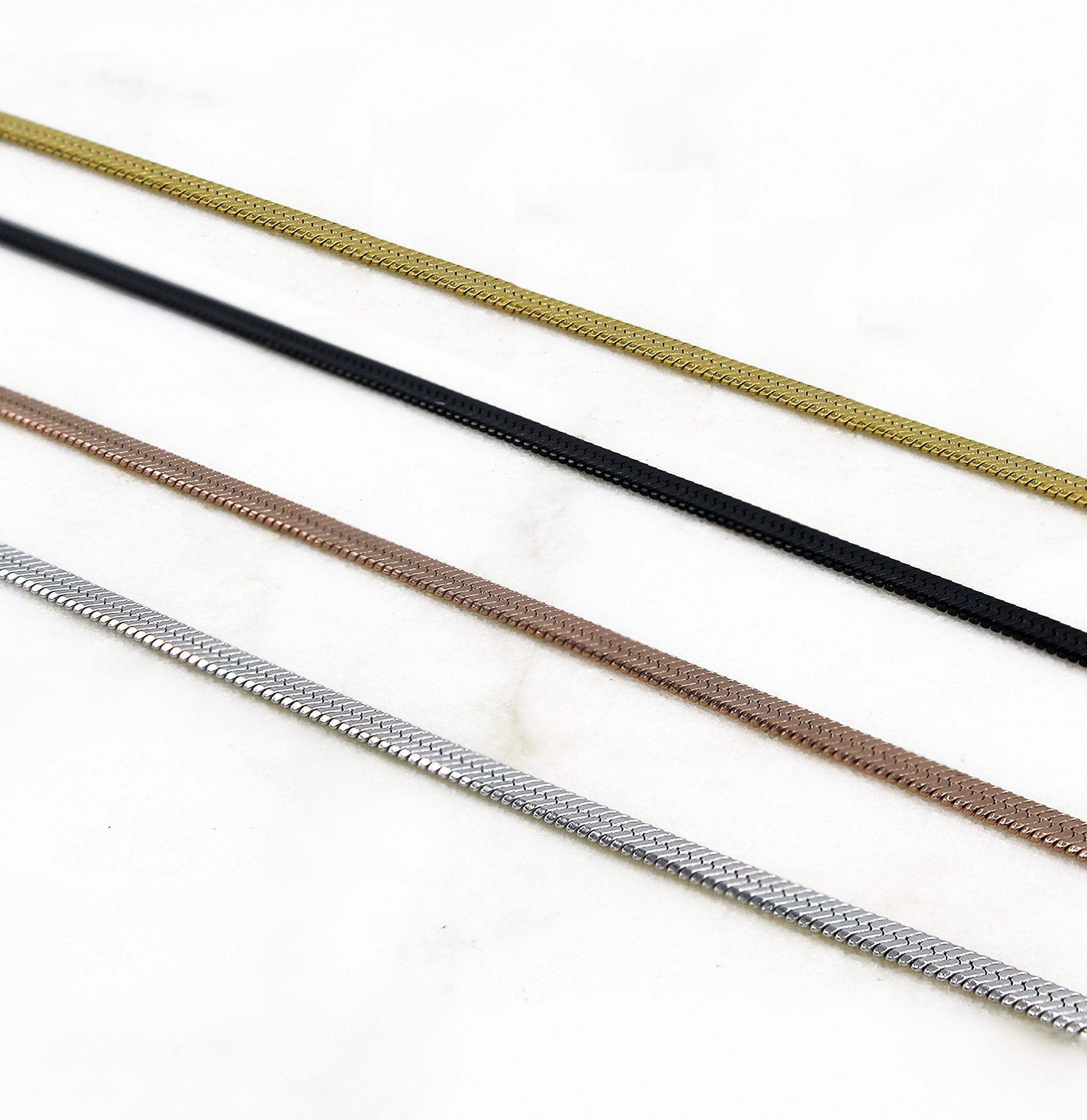 shot of the of the gunmetal, silver, gold and rose gold herring bone chains side by side on marble