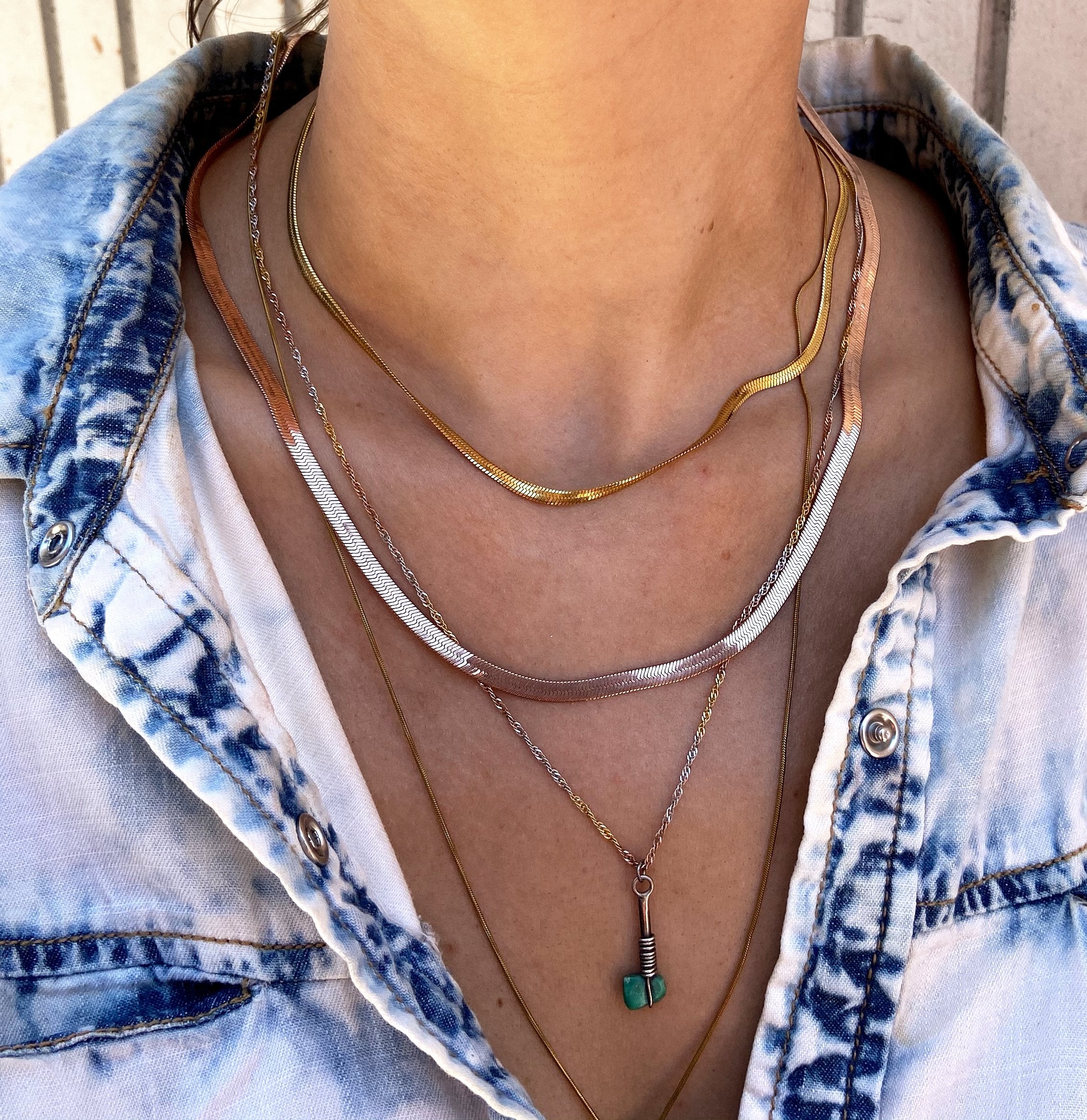 shot of a woman wearing the 3mm and 4mm herring bone chains and other chains in a denim jacket