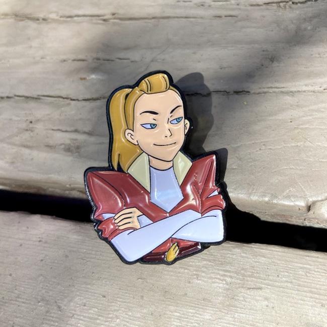 Adora Enamel Pin on a wooden table from she-ra and the princesses of power