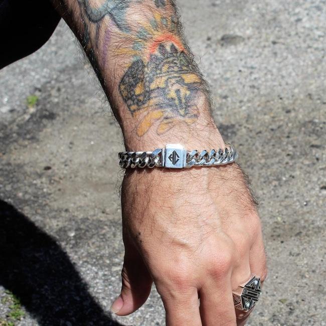 shot of a man with tattoos wearing the classified chain bracelet