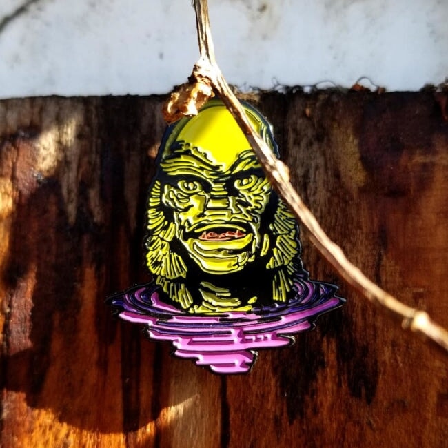 shot of the creature lurking enamel pin on a wooden background