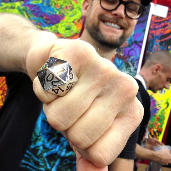 shot of the artist skinner wearing a silver d20 ring with his artwork displayed in the background