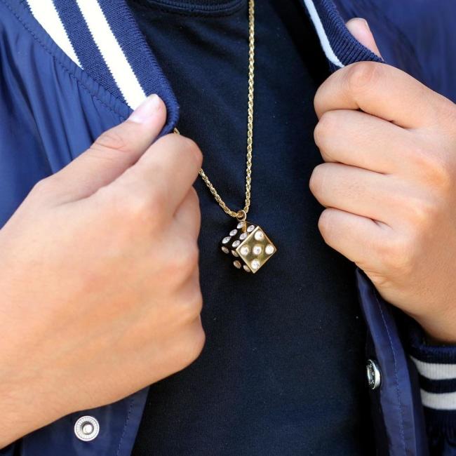 shot of a man wearing a blue bomber jacket wearing a Dice pendant in gold 