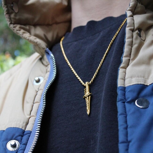 photo of a man in a vintage jacket showing the gold green ranger dragon dagger pendant on a chain