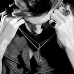 black and white shot of a man holding up the drink ticket pendant