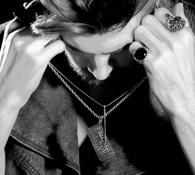 black and white shot of a man holding up the drink ticket pendant