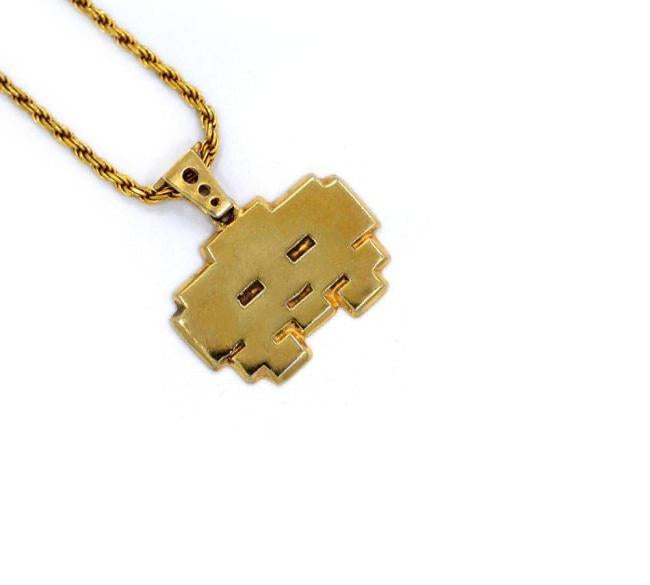 left angle view of the grumpy invader pendant in gold on a white background