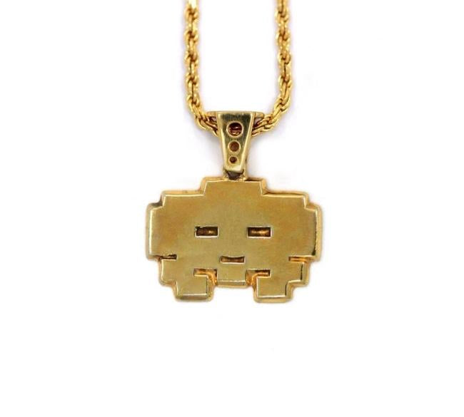 front view of the grumpy invader pendant in gold on a white background