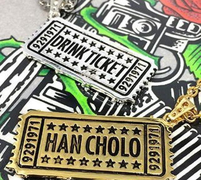 shot of the drink ticket pendant in gold and silver on the hc roses graphic t shirt