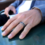 man wearing the his till death do us part ring on his hand on a green table