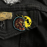 Wolfman brown enamel pin with yellow moon on a black denim jacket