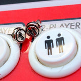 video game earrings player 1 player 2 stud earrings on the player 2 button of an arcade machine