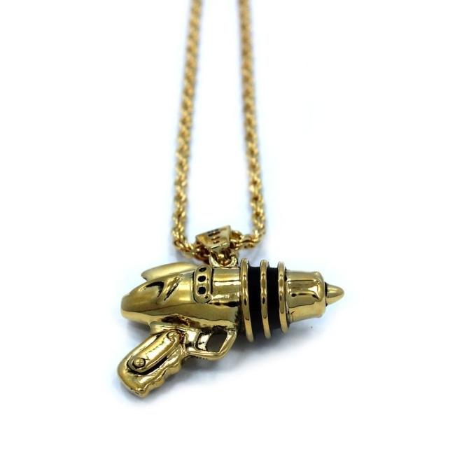 left up close shot of the Ray Gun Pendant in gold on a white surface