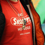 shot of a man in a red graphic t shirt wearing the robot pendant and the ray gun pendant in gold