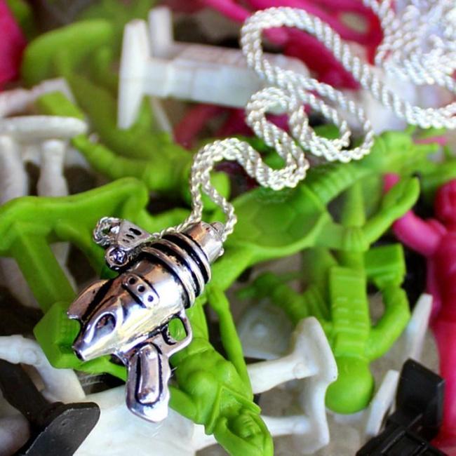 shot fo the ray gun pendant in silver on a colorful alien background