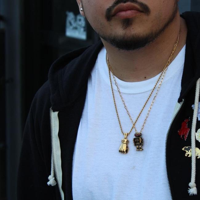 shot of a man wearing the first of fury and robot pendant in gold in a white shirt and black hoodie