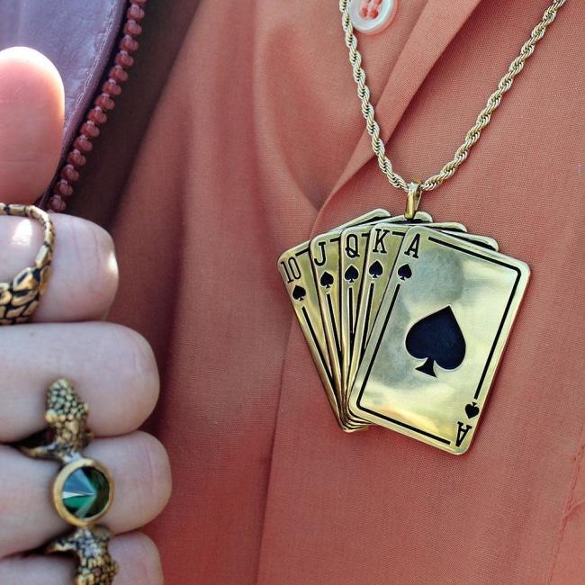 shot of a man in an orange shirt wearing the royal flush pendand with gold rings on