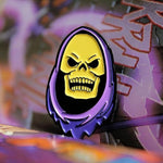 shot of the skeletor enamel pin on purple background