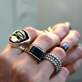 shot of the skeletor ring on a womans hand wearing multiple other rings