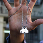 shot of a man holding up the smiley invader pendant with the chain wrapped around his hand