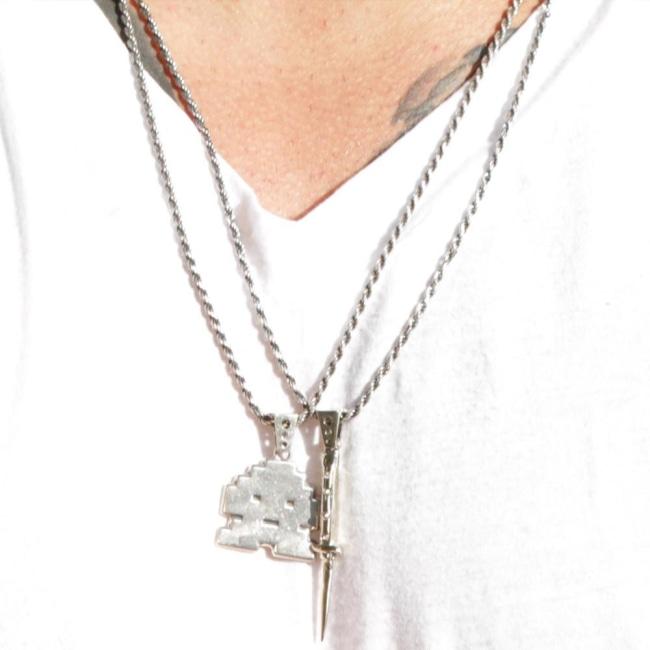 shot of a man wearing the switchblade and stoney invader pendants in silver in a white shirt
