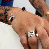shot of a man wearing the tri-klops ring as well as the havoc cuff leaning on a white wall