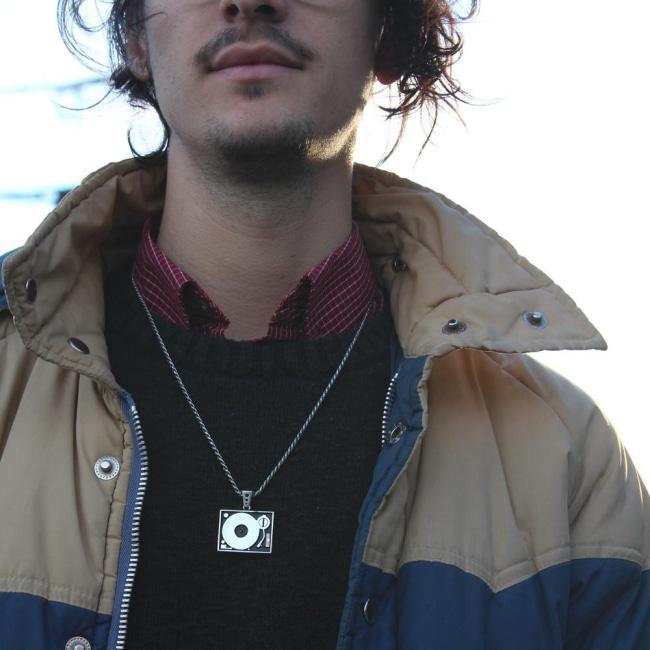 shot of a man in a jacket wearing the turntable pendant in silver 